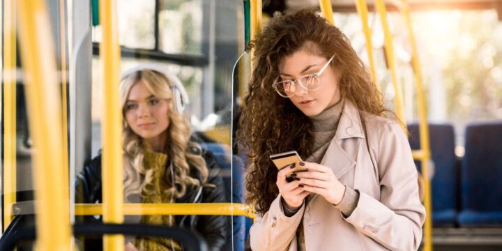 Orimlig Hyra - En kvinna på en buss kollar på sin mobiltelefon