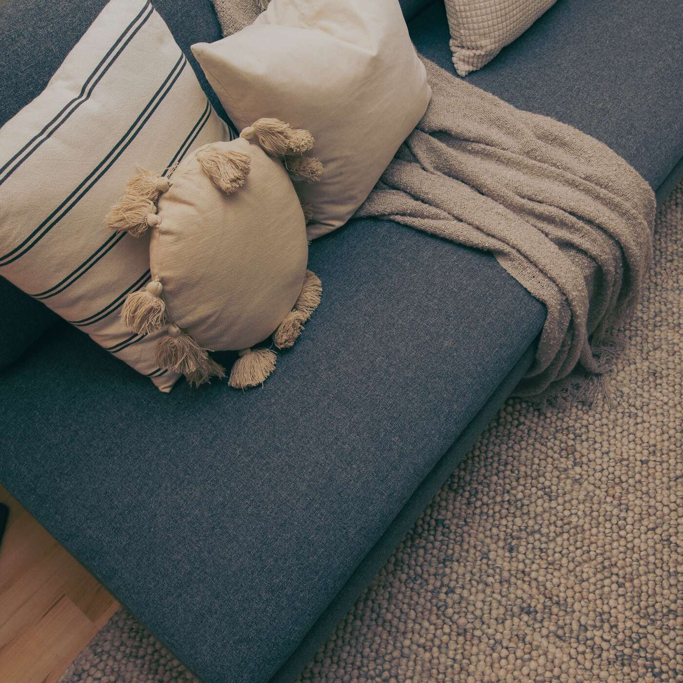 Grå soffa med kuddar och matta i beiget