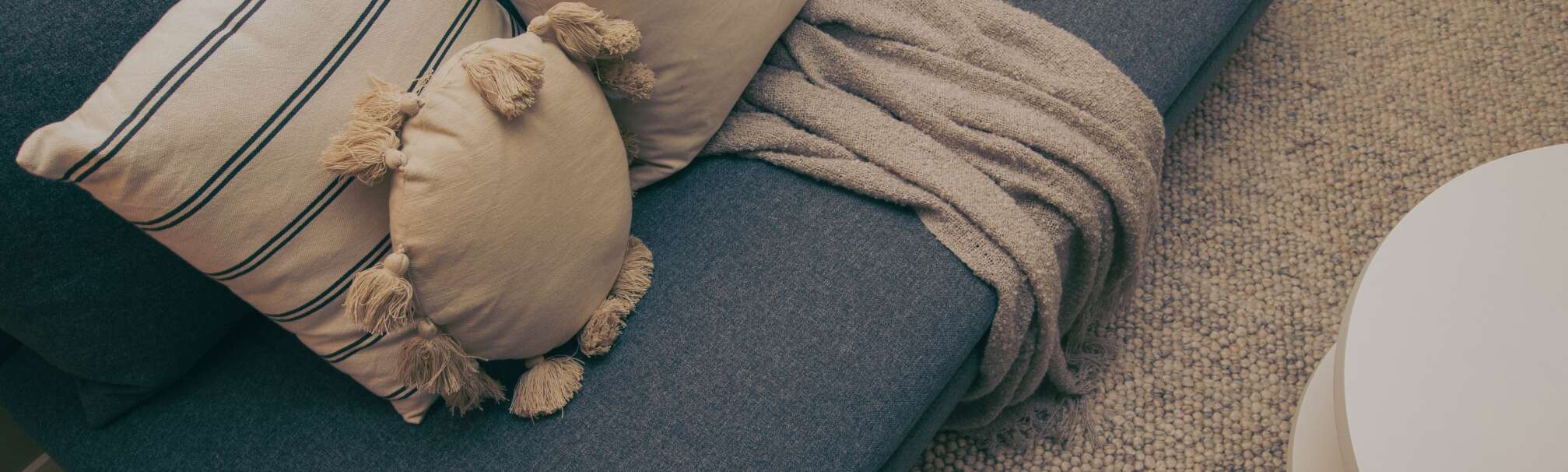 Grå soffa med kuddar och matta i beiget